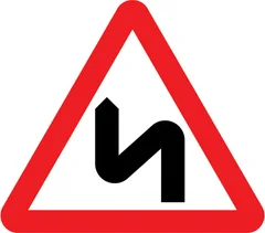 Double bend or series of bends ahead, first to the left — UK road sign